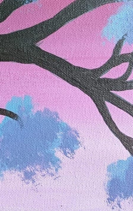 A close up crop, showing blue foliage brown branches and a light pink sky. 